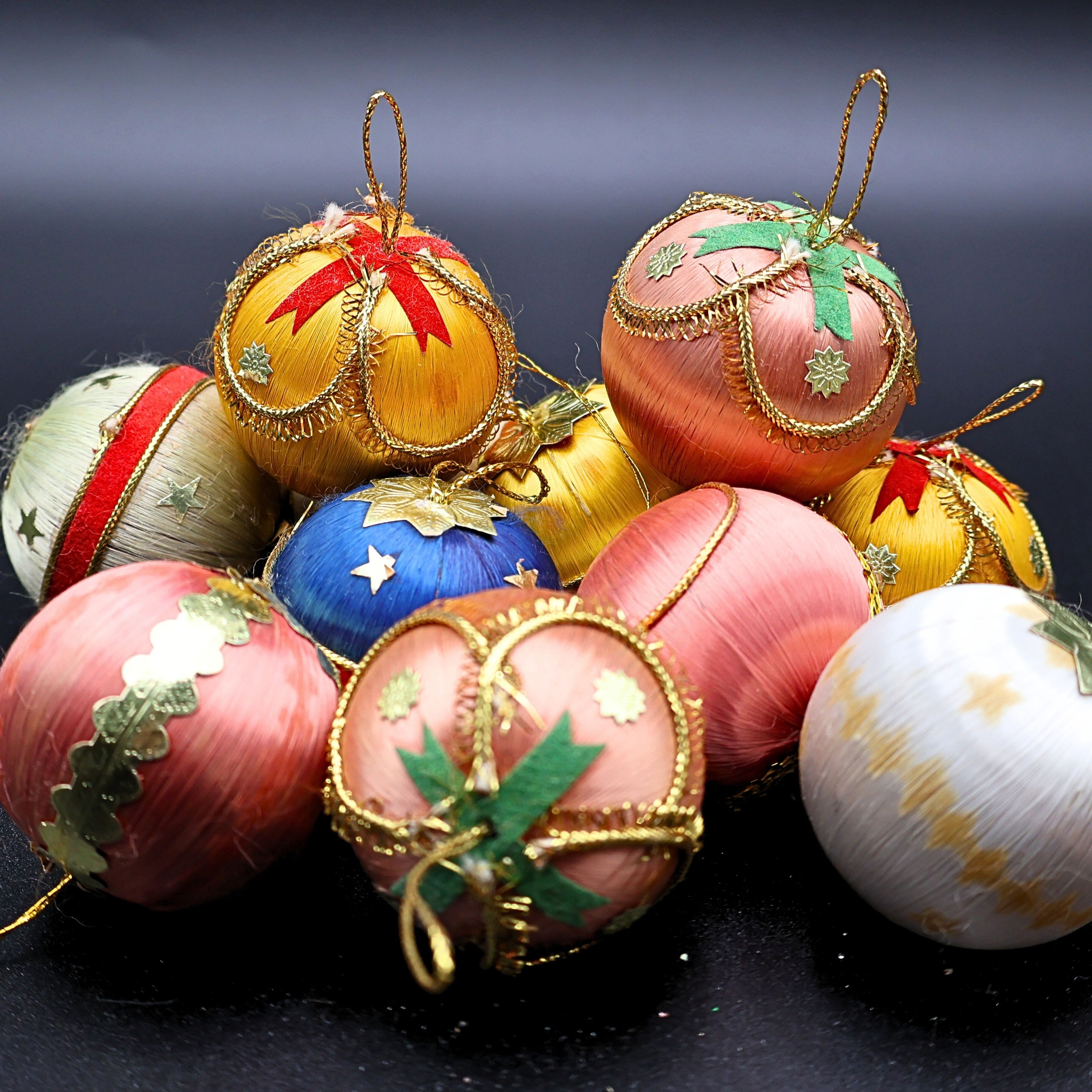 Vintage satin wrapped Christmas ornaments arranged together showing multiple colors and gold accents, perfect for retro holiday decor, cozy Christmas styling, and nostalgic seasonal displays