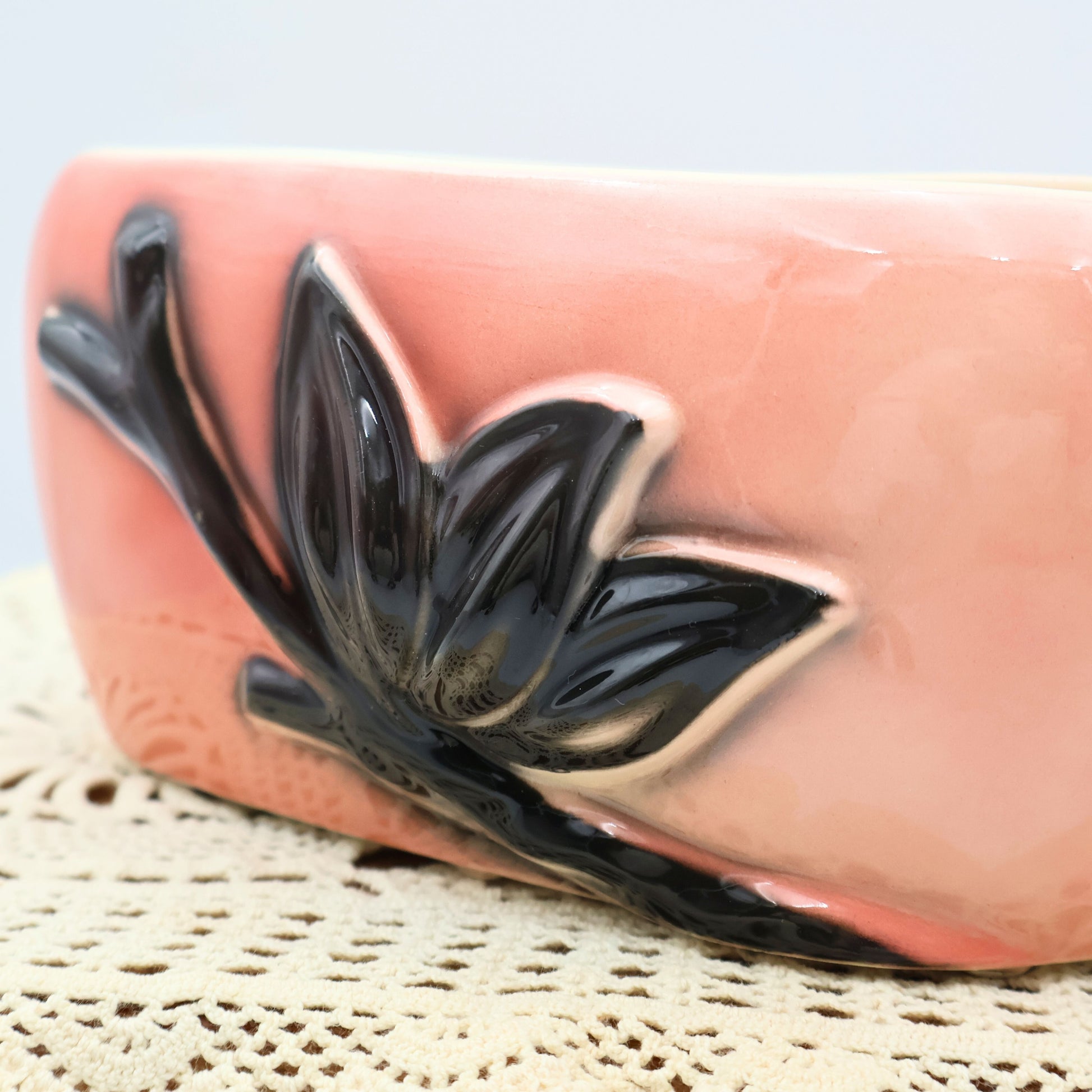 Close-up detail of raised black floral and leaf motif on vintage Royal Copley pink ceramic planter.