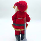 Rear view of the vintage Sakai Santa doll in a red fabric suit and drooping cap with cream-colored trim. His black belt, attached cloth tag, black boots, and the upright gray metal stand with a curved wire support are visible against a plain pale background.