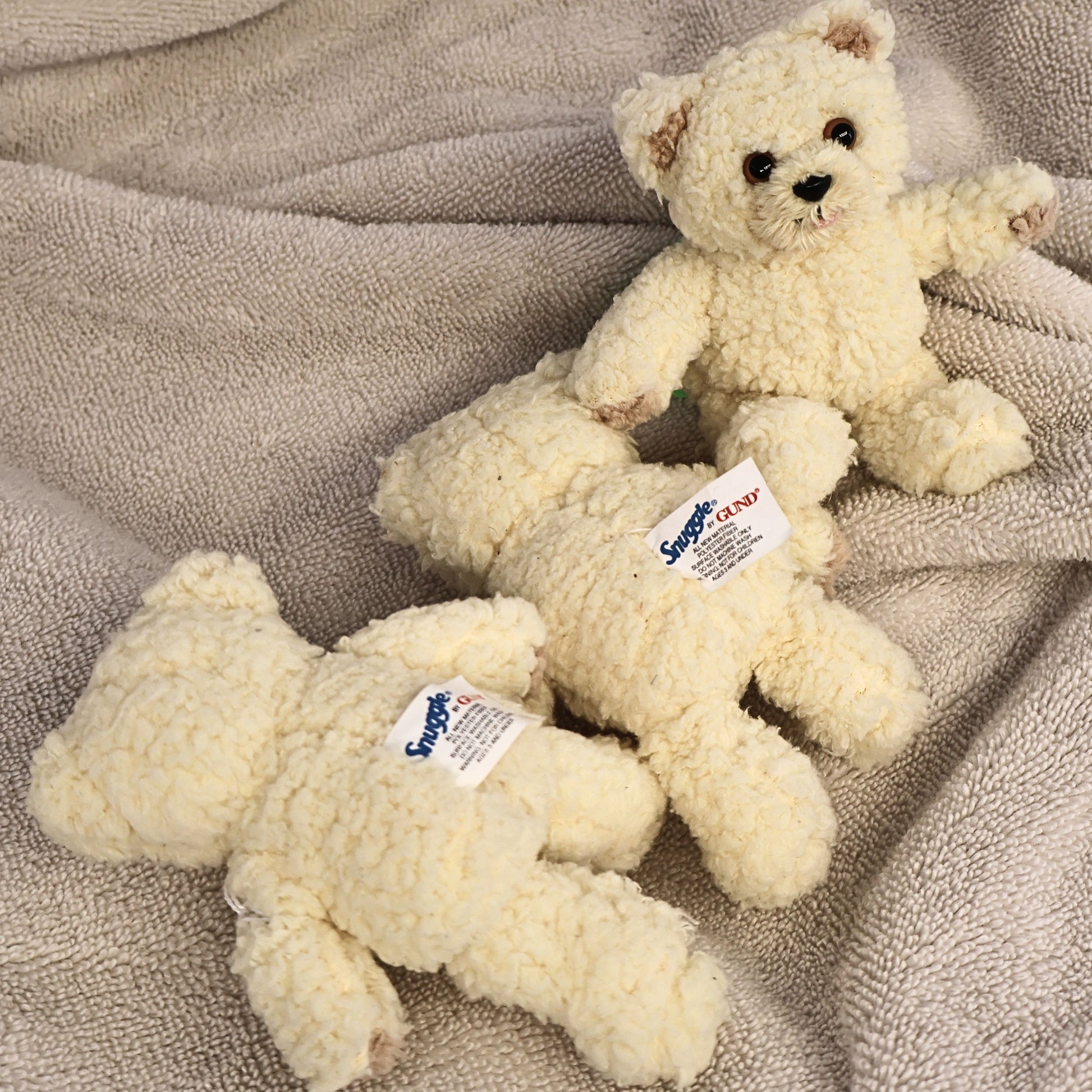 Rear view of three vintage Snuggle by GUND plush bears displaying their original manufacturer labels. This image highlights authentic sewn tags and the overall condition of each collectible plush for vintage toy and advertising memorabilia buyers.
