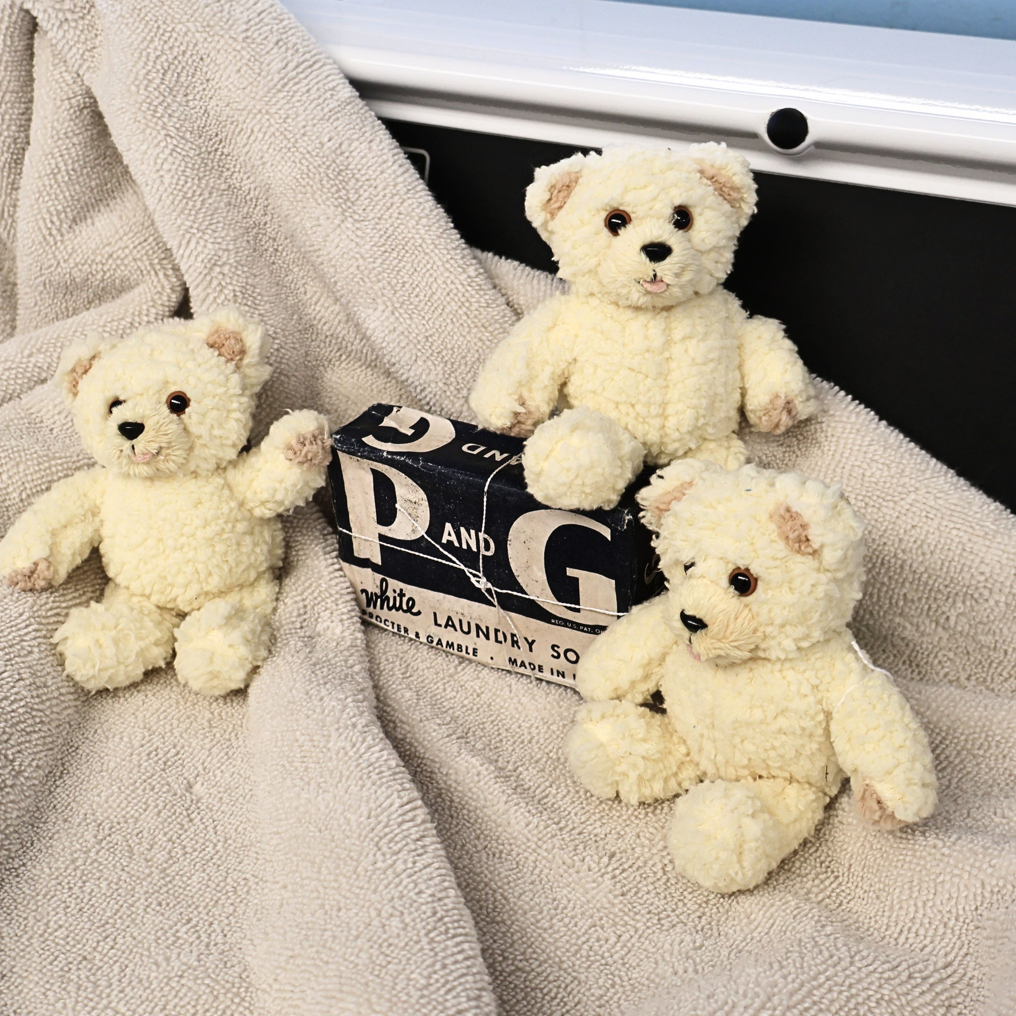 Three vintage Snuggle by GUND plush mascots arranged around a vintage Procter & Gamble laundry soap package. The cozy display highlights their charming expressions and fluffy cream fur, ideal for collectors of advertising memorabilia, GUND plush, and nostalgic home decor.