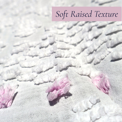 Macro photograph showing the luxuriously soft raised chenille texture on a vintage white bedspread with lavender floral accents. Beautiful for farmhouse decor, cottage bedrooms, heirloom bedding collections, vintage textiles, and romantic interior decorating.