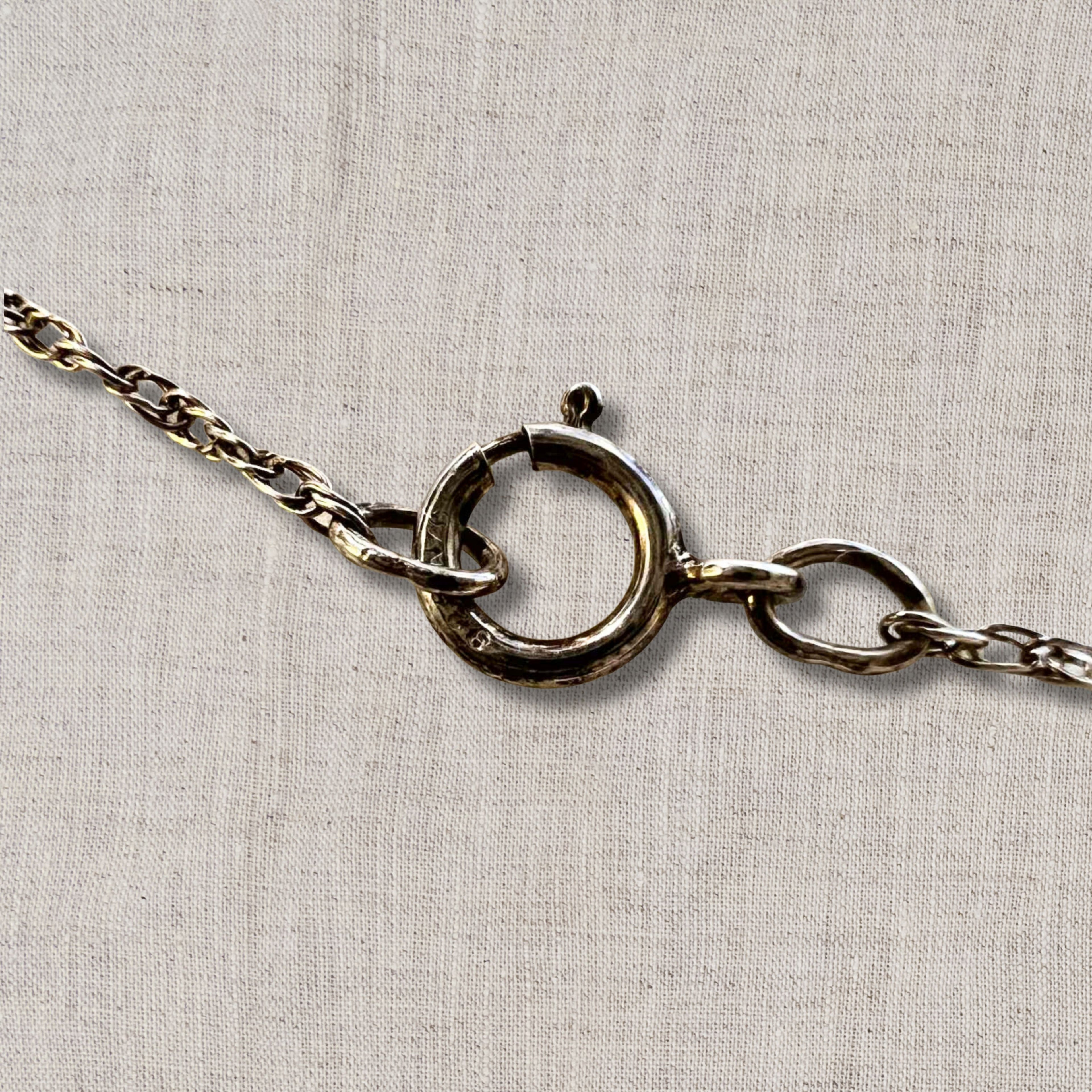close up of sterling silver spring ring clasp on vintage necklace chain, secure closure detail for 18 inch coin pendant necklace, authentic silver chain hardware showing craftsmanship and wear consistent with vintage jewelry condition
