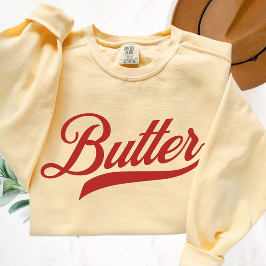 Flat lay of unsalted butter script crewneck sweatshirt in yellow. Clean vintage graphic design with bold script lettering. Comfortable cotton blend pullover perfect for layering and everyday wear.