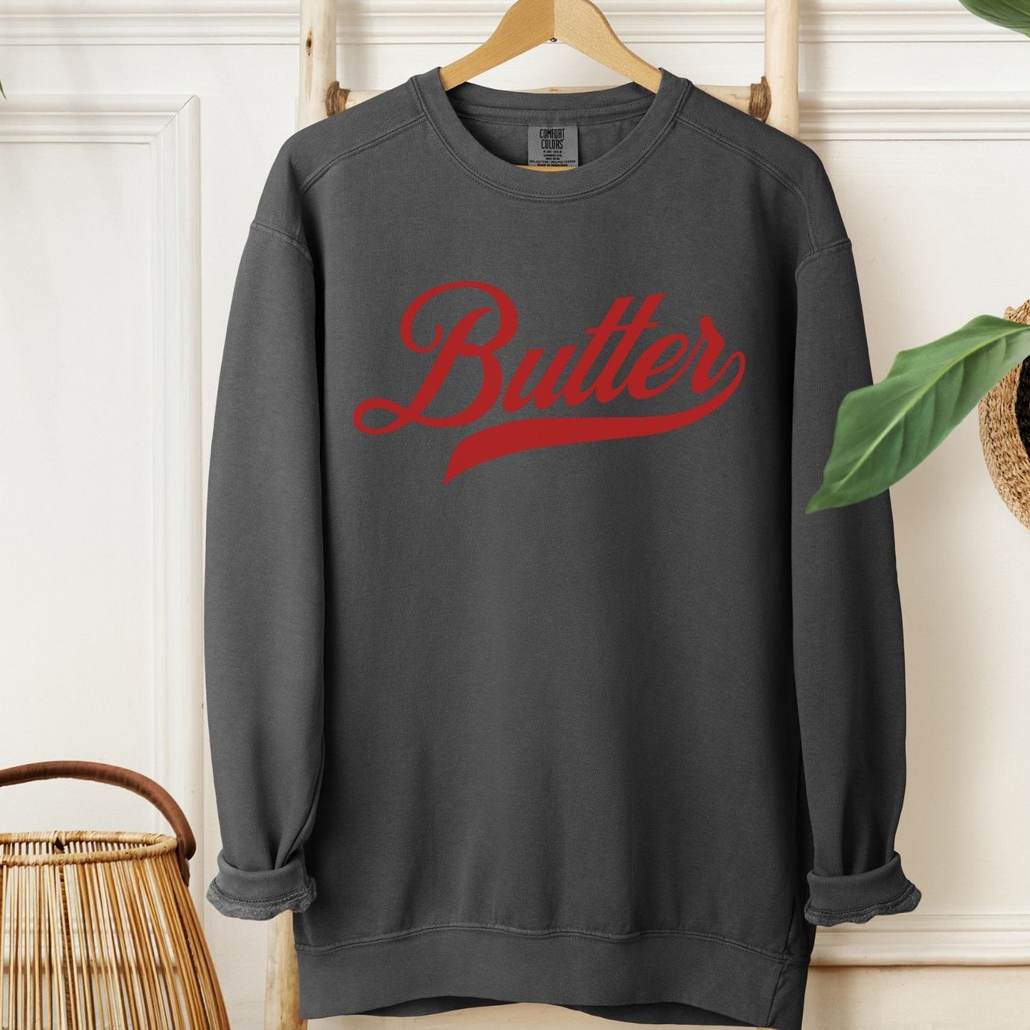 Gray unsalted butter script sweatshirt with bold red lettering. Cozy unisex crewneck pullover designed for comfort and style. Great gift idea for butter lovers and fans of playful graphic apparel.