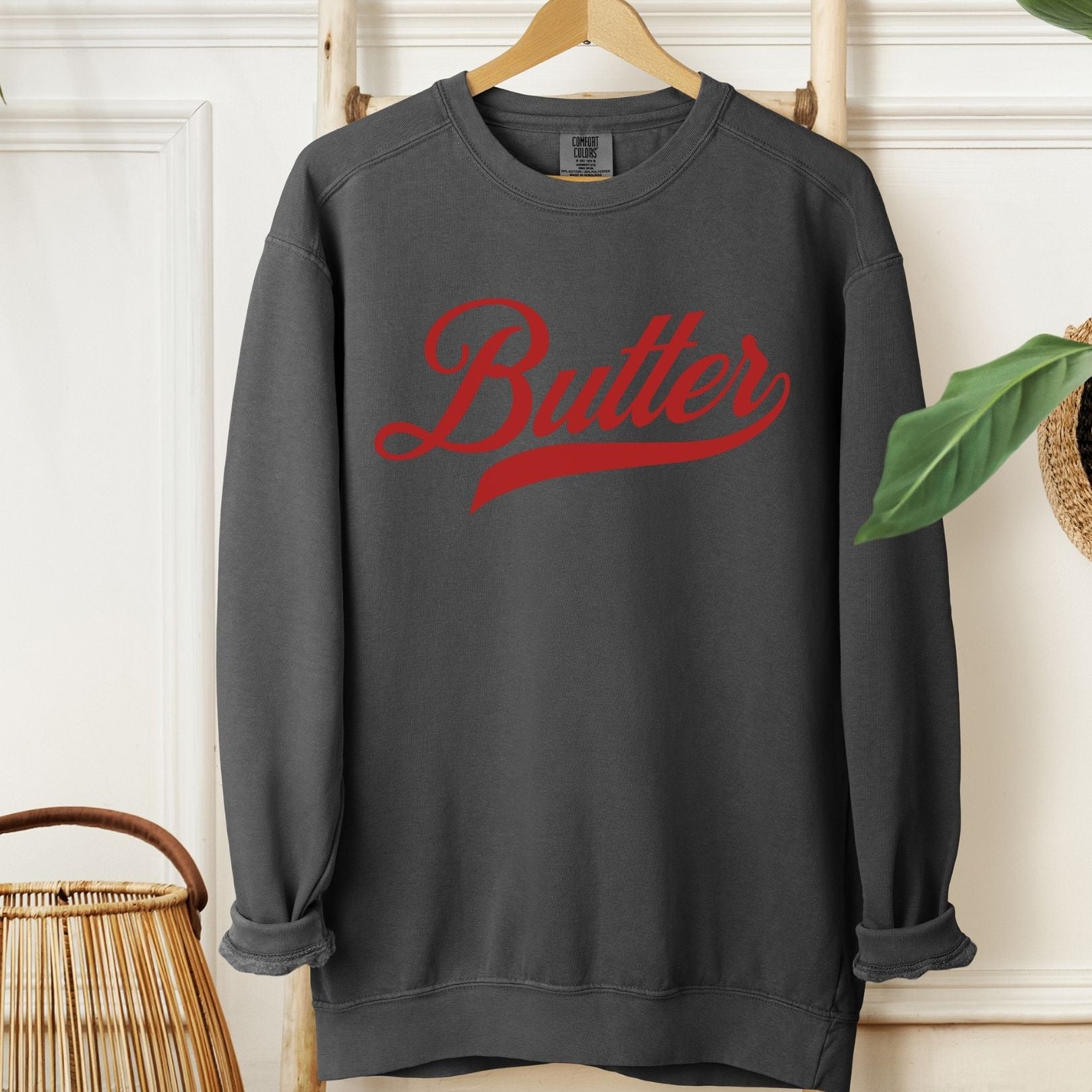 Gray unsalted butter script sweatshirt with bold red lettering. Cozy unisex crewneck pullover designed for comfort and style. Great gift idea for butter lovers and fans of playful graphic apparel.