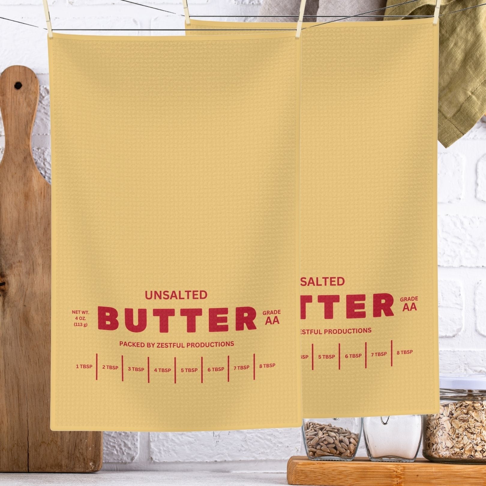 Unsalted butter tea towel hanging in kitchen with bold butter label design and red lettering. Absorbent microfiber towel for everyday use and playful kitchen decor.