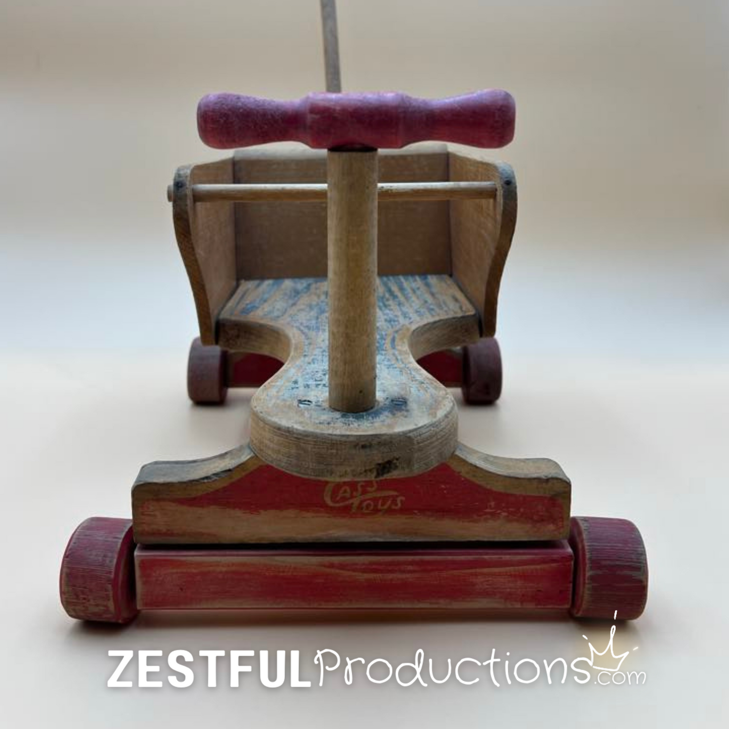 Front view of a vintage 1950s Cass Toys wooden doll push cart with red wheels