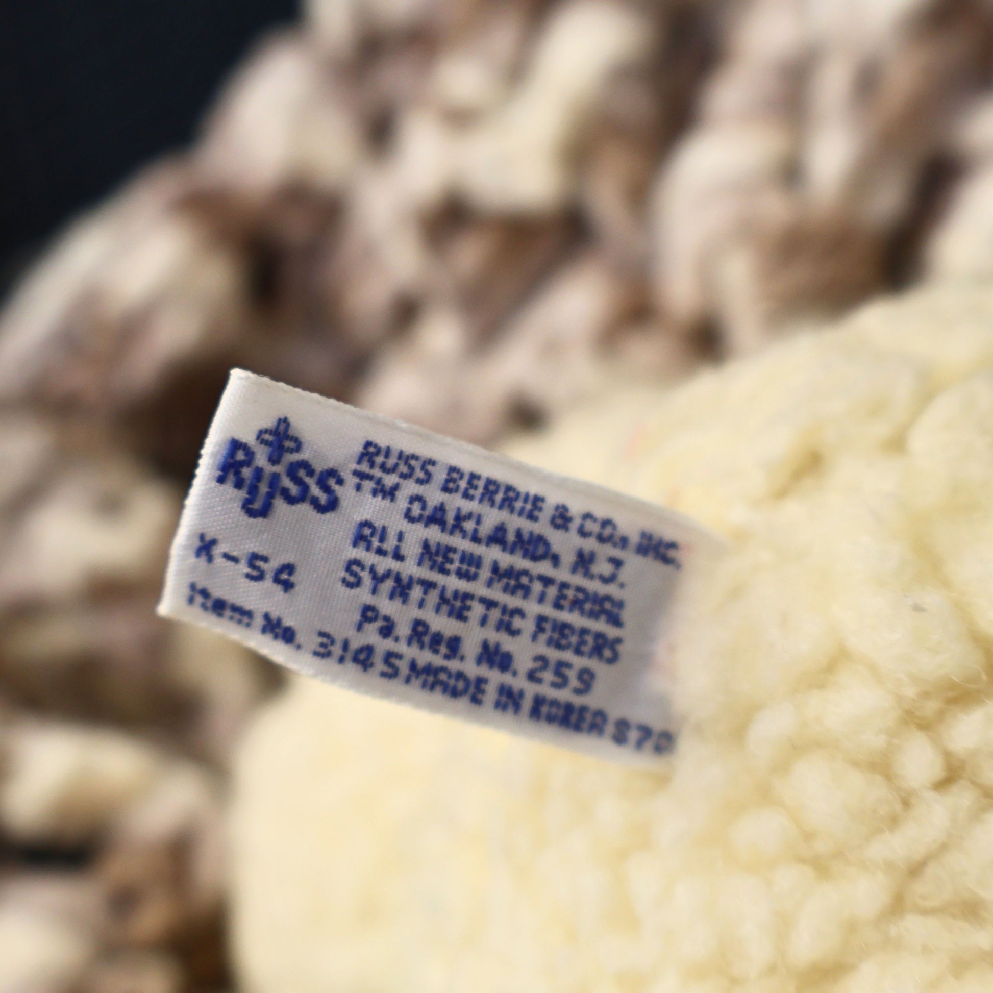 Close-up photograph of the original Russ Berrie & Co. manufacturer tag on an authentic 1986 Snuggle Bear plush by Lever Brothers. The intact production label adds collector appeal for buyers seeking genuine vintage advertising and plush collectibles.