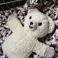 Vintage 1986 Snuggle Bear hand puppet by Lever Brothers shown from the front on a soft textured blanket. This classic cream plush advertising mascot features an embroidered smile, original design details, and makes a charming collectible for laundry room decor or nostalgic vintage toy displays.