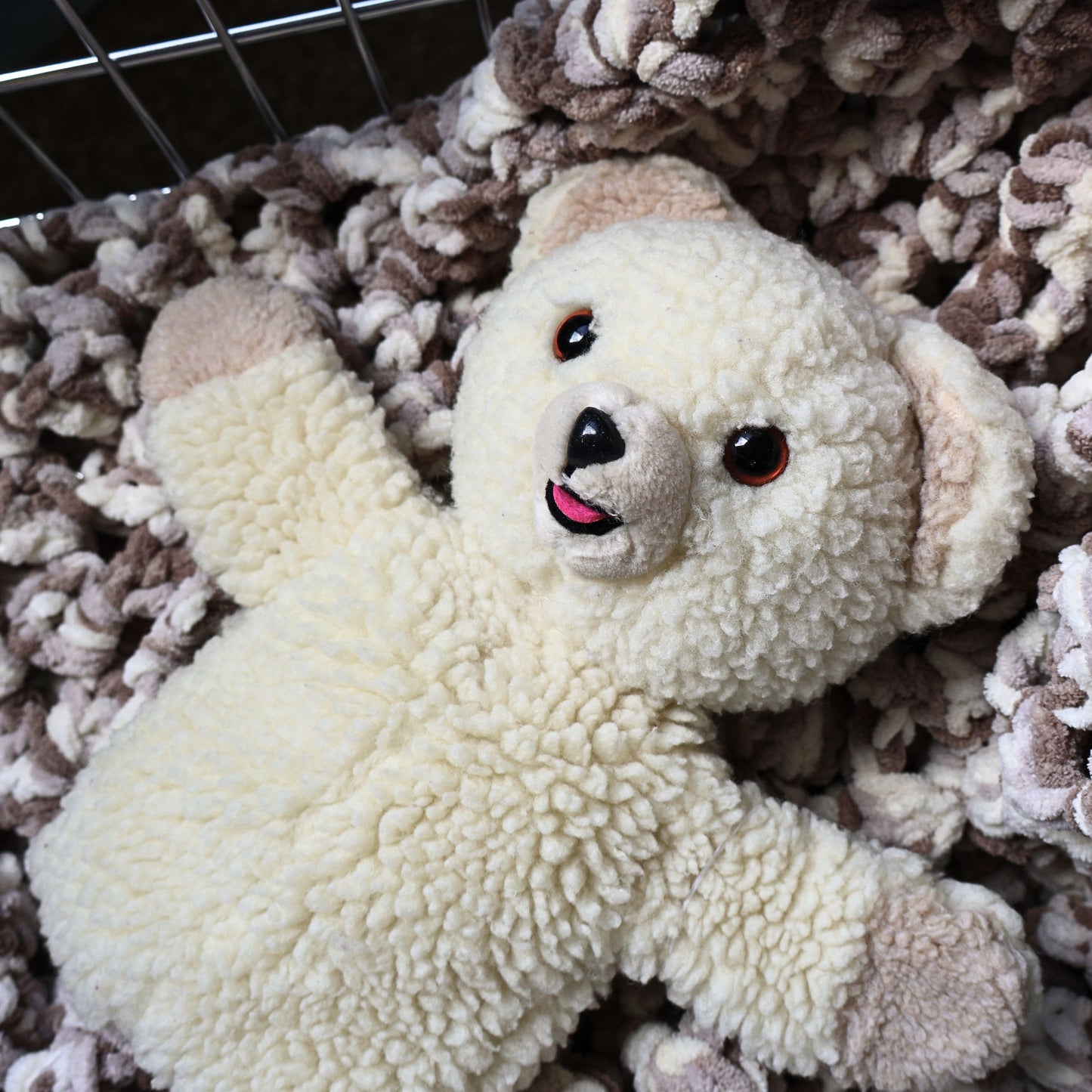 Vintage 1986 Snuggle Bear hand puppet by Lever Brothers shown from the front on a soft textured blanket. This classic cream plush advertising mascot features an embroidered smile, original design details, and makes a charming collectible for laundry room decor or nostalgic vintage toy displays.