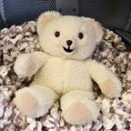 Vintage 1986 Snuggle Bear by Lever Brothers Company sitting on a cozy knit blanket. This original 15-inch advertising mascot features soft ivory sherpa plush, original tags, and a friendly smiling face, making it a charming collectible for nostalgic home decor, vintage plush collections, and childhood memory displays.