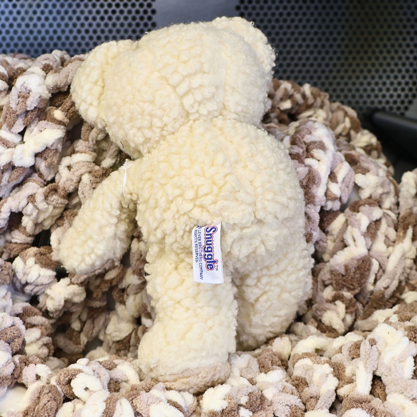 Rear view of a vintage 1986 Snuggle Bear plush featuring the original sewn-in Snuggle copyright tag. The fluffy cream plush and authentic label make this advertising mascot an appealing collectible for vintage decor, laundry room displays, and nostalgic toy collections.