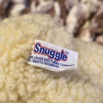 Close-up of the original Snuggle fabric tag attached to a 1986 Lever Brothers Snuggle Bear plush, confirming authenticity for collectors of vintage advertising memorabilia, retro plush toys, and nostalgic fabric softener mascots.