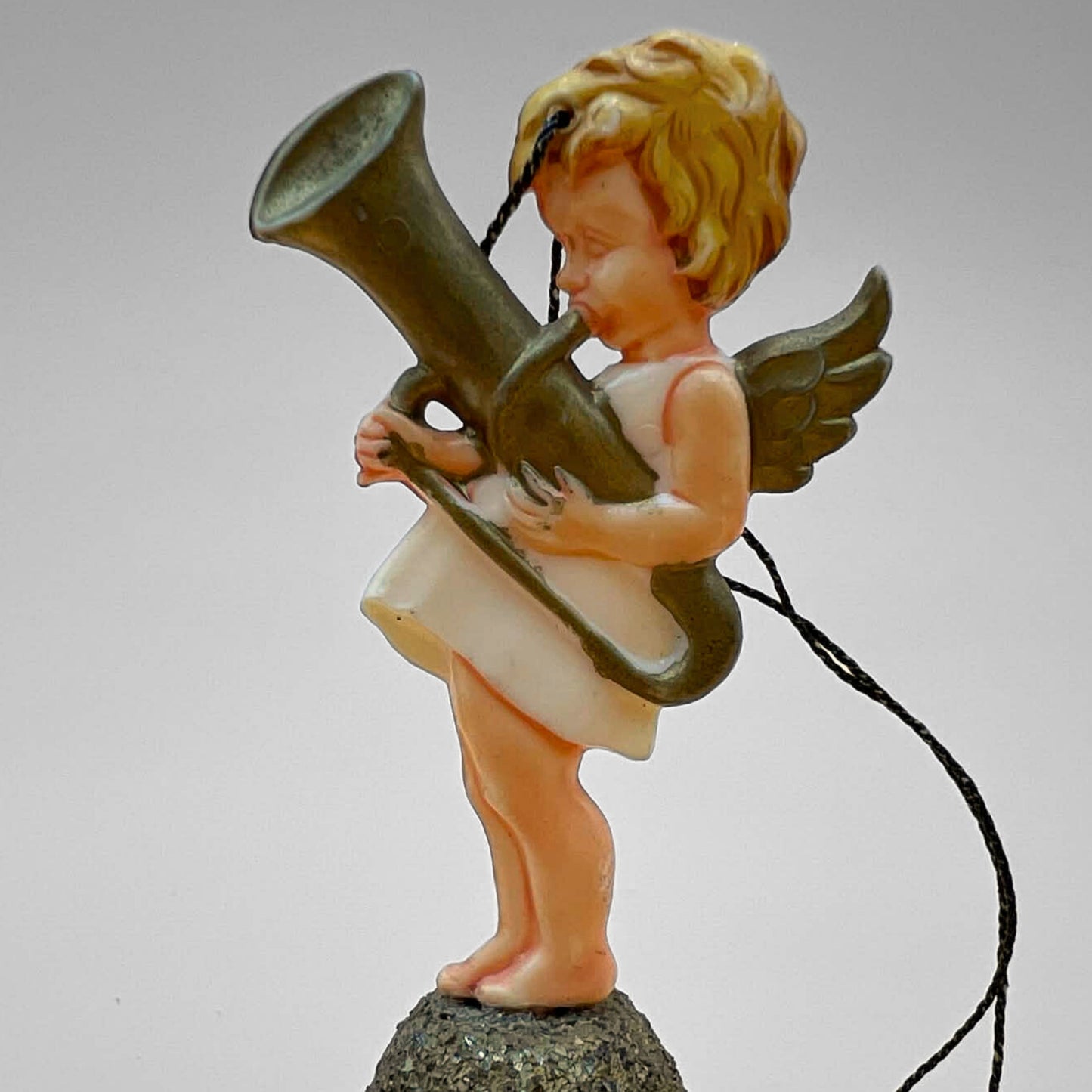 Single vintage angel bell ornament featuring cherub playing a horn instrument standing on a gold glitter bell. Side profile shows wing detail and hanging string. Mid century West Germany Christmas ornament collectible