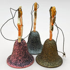 Back view of vintage angel bell ornaments showing detailed cherub figurines and original hanging strings. Glitter bell bases in pink, silver, and gold with aged texture. Mid century West Germany Christmas ornaments collectible set