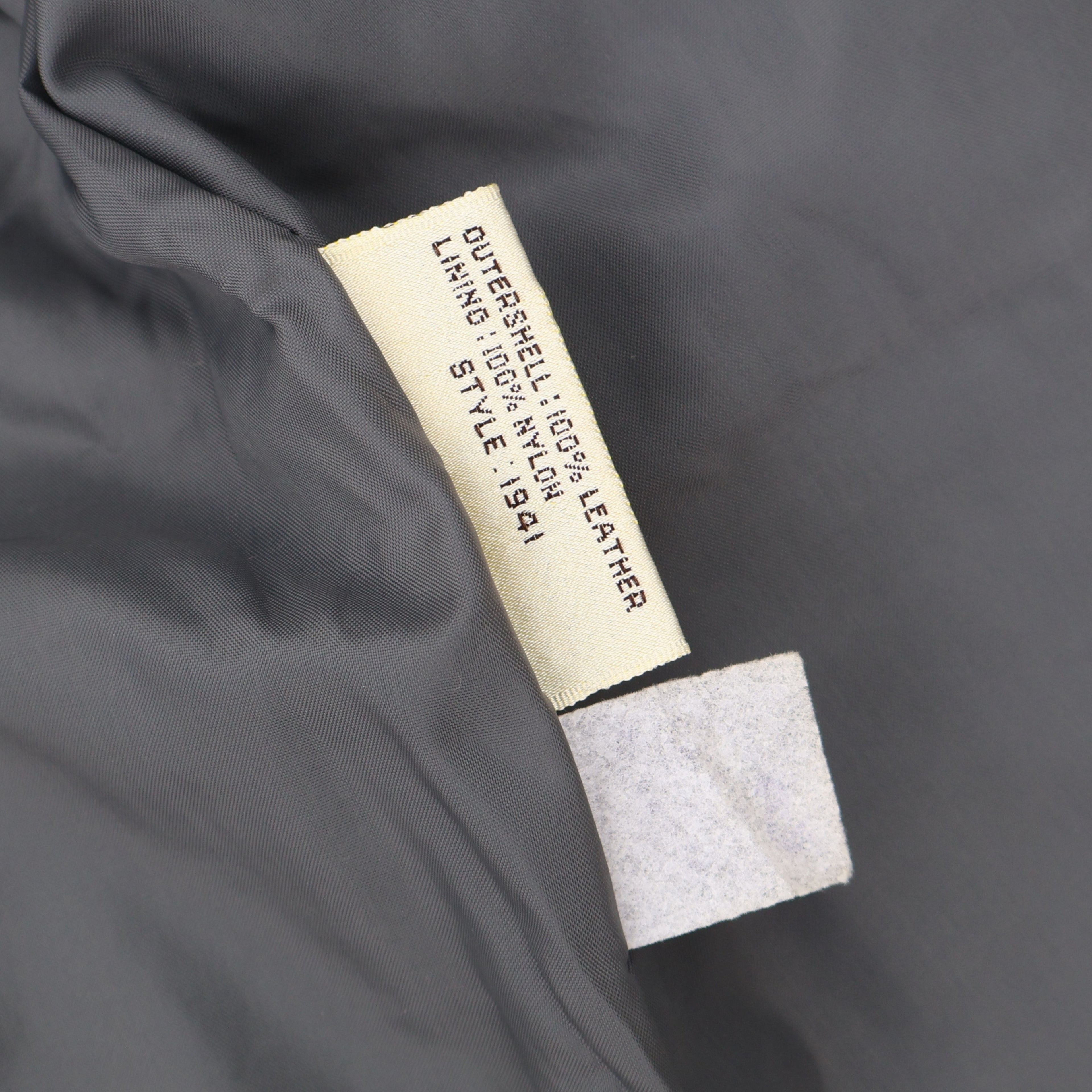 Material tag inside vintage gray leather blazer showing 100 percent leather outer shell.