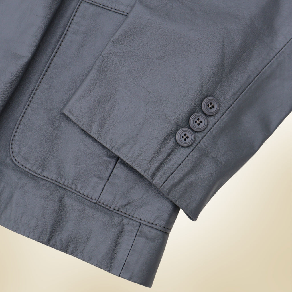 Close up of gray leather blazer sleeve showing four-button cuff detail and smooth leather texture.