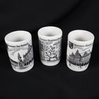 Set of three vintage Bremen Germany porcelain shot glasses arranged against a black background. The white cylindrical cups feature black architectural illustrations labeled Bremen Der Roland, Bremen Stadtmusikanten, and Bremen Rathaus, with their open rims visible.