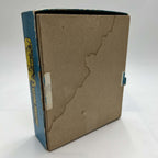 Underside of the original vintage Built-Rite Ours to Protect puzzle box, showing the plain brown cardboard base, visible water damage, and tape remnants along the sides. The worn blue lid surrounds the base, with part of its yellow and black side graphic visible.