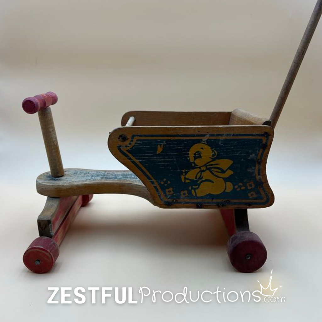 Side profile of the vintage Cass Toys doll stroller showing the original blue bear illustration, red wooden wheels, solid wood body, and tall rear push handle designed for children to push dolls and teddy bears.