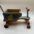 Opposite side of the vintage wooden doll stroller displaying the original blue bear artwork, natural wood finish, red painted wheels, and classic mid-century American toy design.