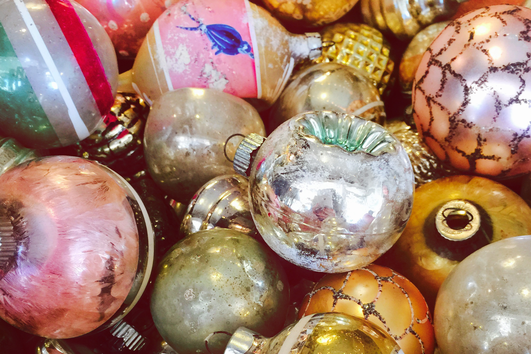 Close-up of vintage glass Christmas ornaments in gold, pink, and metallic tones, showcasing retro holiday decor and nostalgic seasonal styling