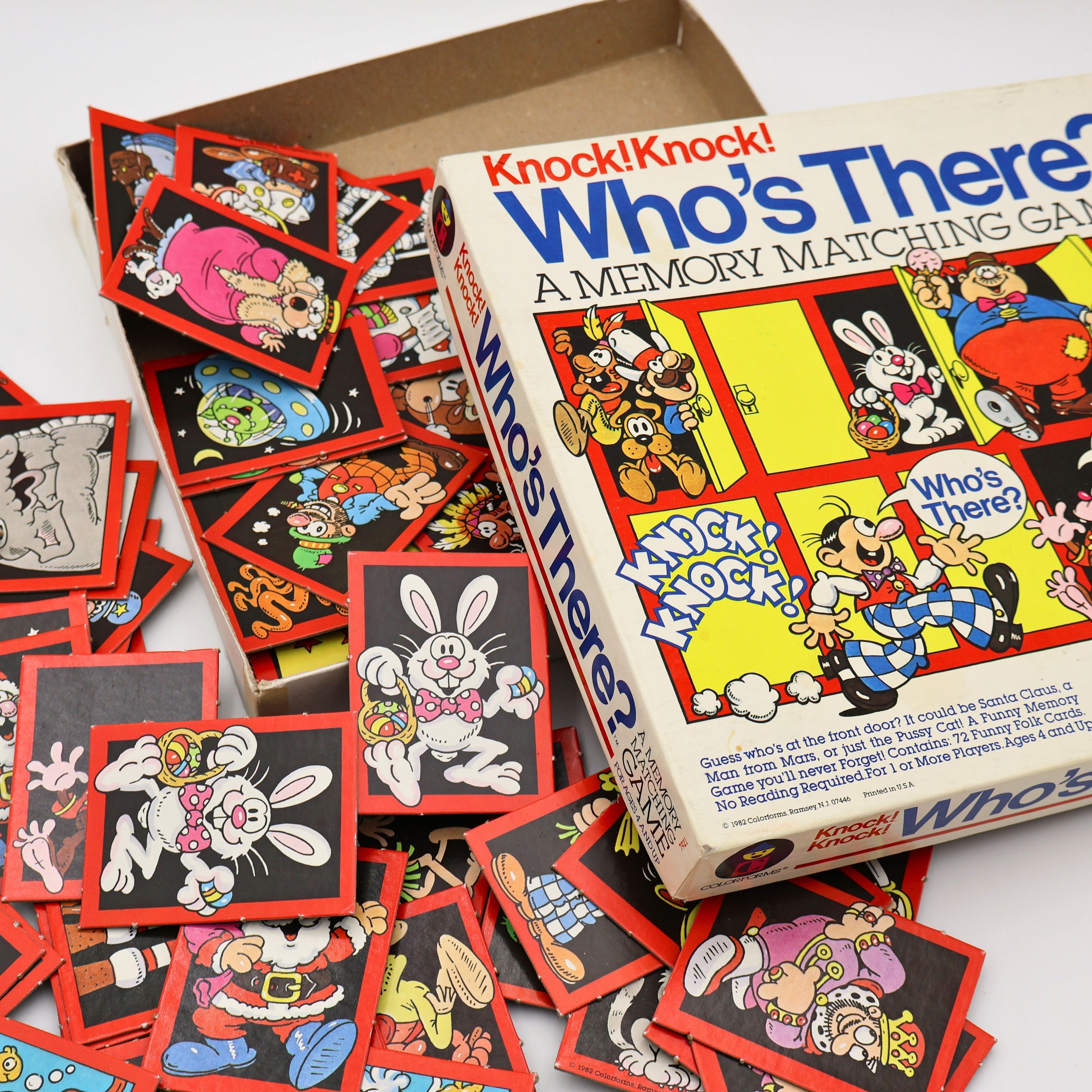 Assorted illustrated character matching cards from vintage 1982 Colorforms Knock Knock Who’s There memory game spread across surface.