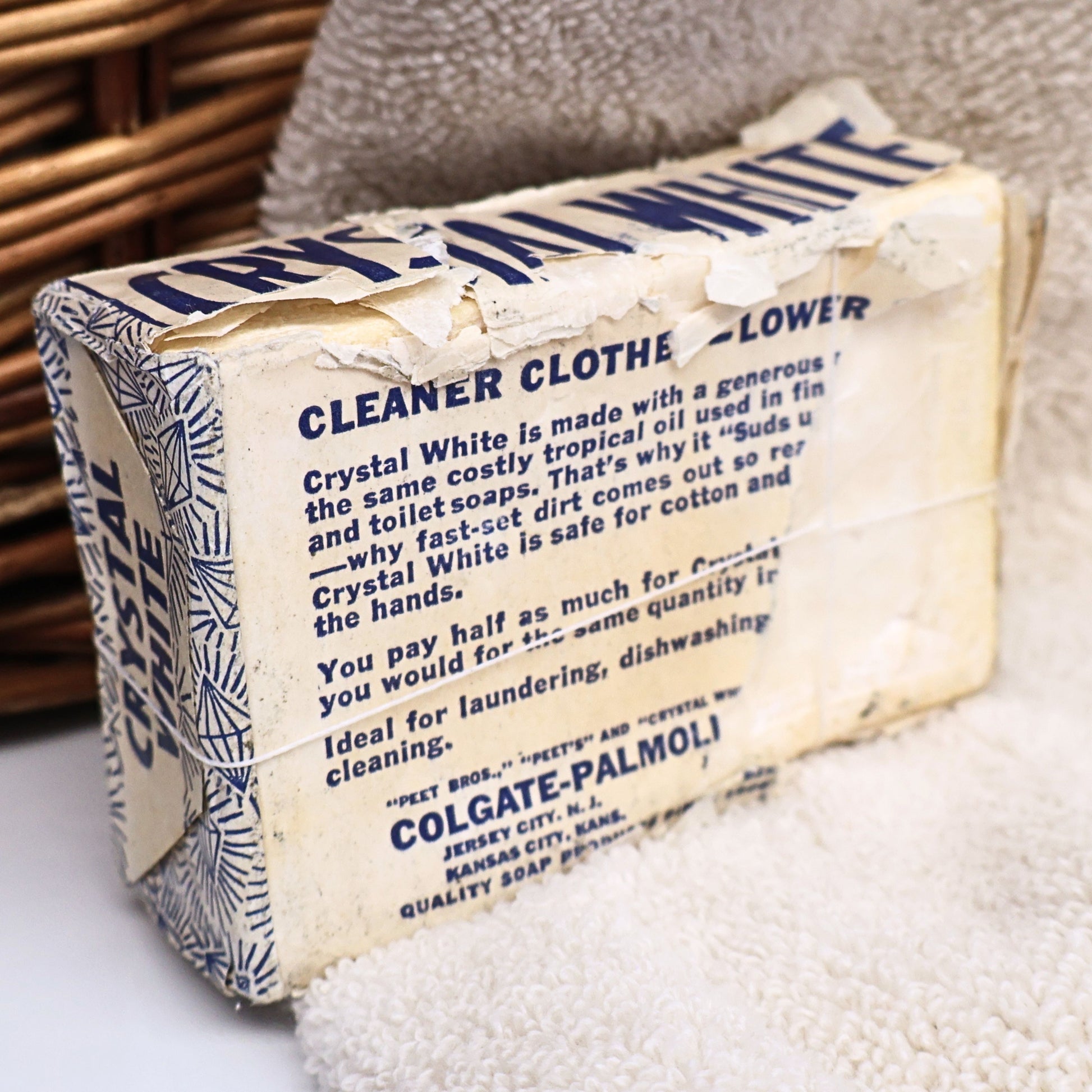 Rear angled view of a vintage Crystal White Family Soap bar highlighting its original paper wrapper, aged folds, and decades of authentic storage wear. A unique Colgate-Palmolive advertising collectible that adds nostalgic character to vintage laundry room decor, photography styling, and farmhouse displays.