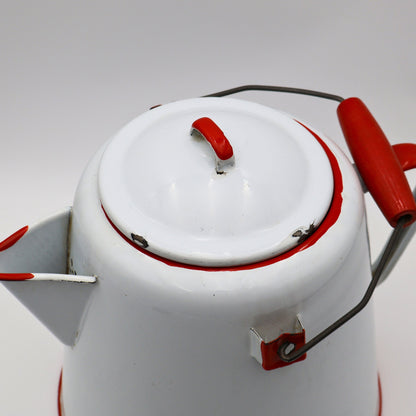 Close up of red trimmed lid on large antique enamel coffee pot with light chipping