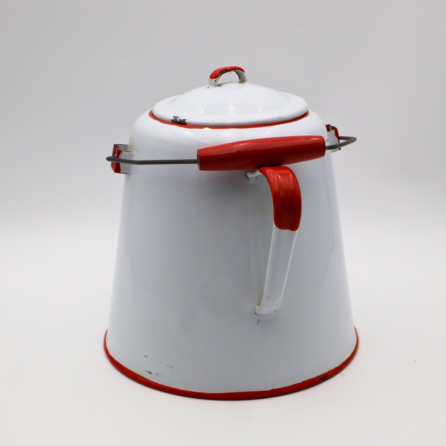 Rear view of large white enamel cowboy coffee pot with red handle and metal bail