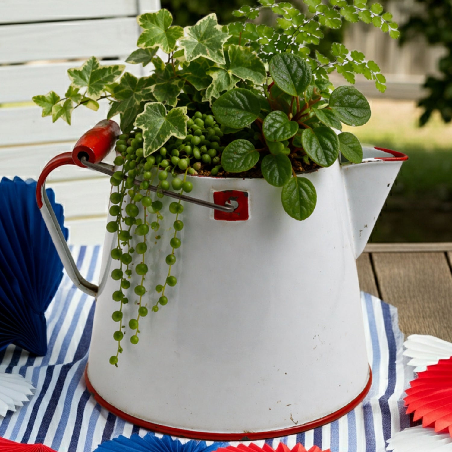 White enamel coffee pot with plants on a tablecloth