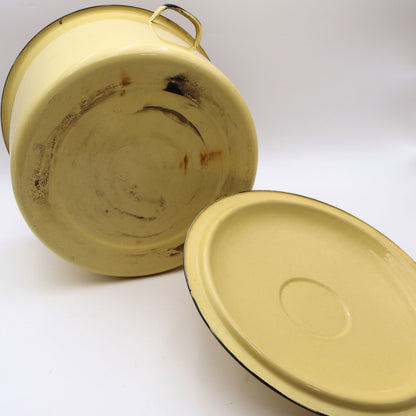 Bottom view of a vintage yellow enamelware stock pot showing authentic enamel wear and age-related finish loss on the underside. These signs of use reflect the history and character of this genuine farmhouse kitchen collectible.