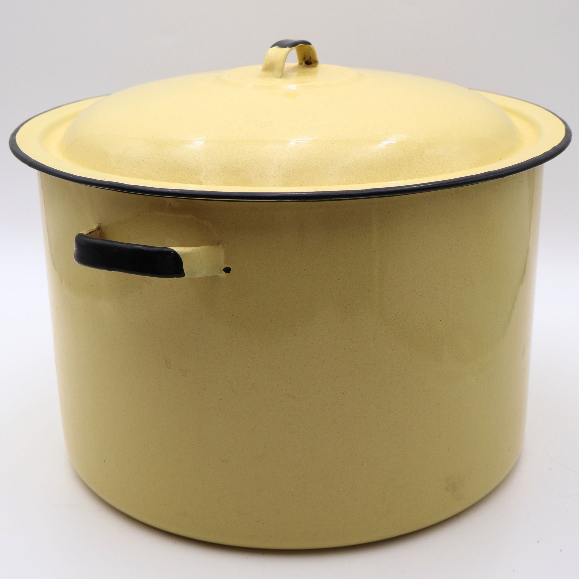Side profile of a vintage yellow enamelware stock pot with matching lid featuring classic black trim, sturdy side handles, and a glossy buttery yellow finish. A timeless vintage farmhouse decor piece with authentic mid-century charm.