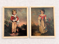 Pair of vintage children’s portrait prints in matching cream wood frames on pale linen. At left, a blond boy in a red jacket holds a small dog; at right, a dark-haired girl in a red bodice and golden skirt holds a white cat beside flowering plants.