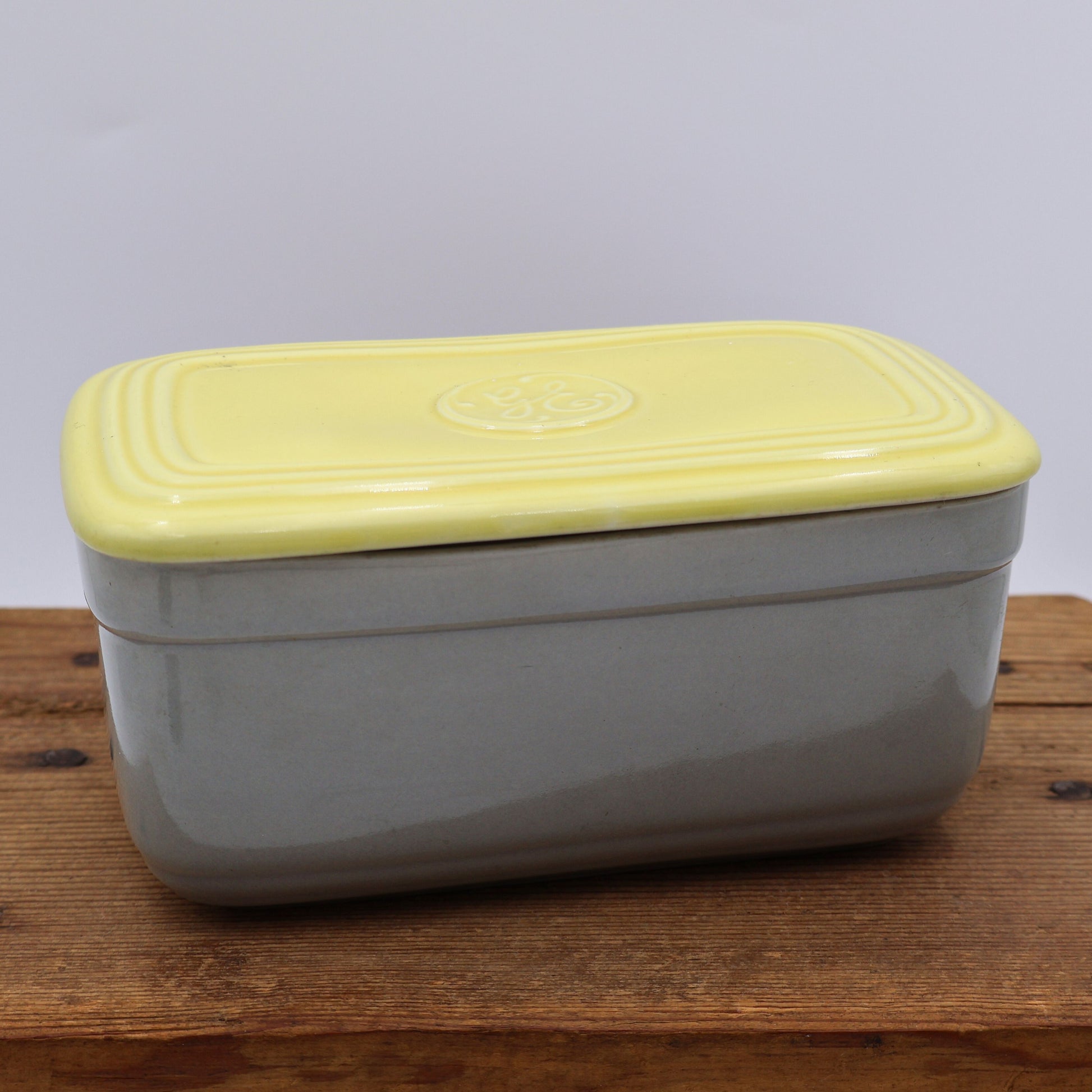 Vintage GE refrigerator dish with lid in yellow and gray Hall China ceramic, mid century kitchen storage container front view.