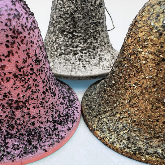 Close-up detail of vintage angel bell ornament bases highlighting textured glitter finish in pink, silver-blue, and gold tones. Surface patina shows authentic mid century wear typical of German Christmas decor collectibles
