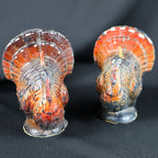 Front view of a pair of vintage Gurley Thanksgiving turkey candles standing side by side. Each approximately three-inch figural candle has a rounded breast, long painted red wattle, molded wings, broad orange-brown tail, dark circular base and visibly aged wax finish.
