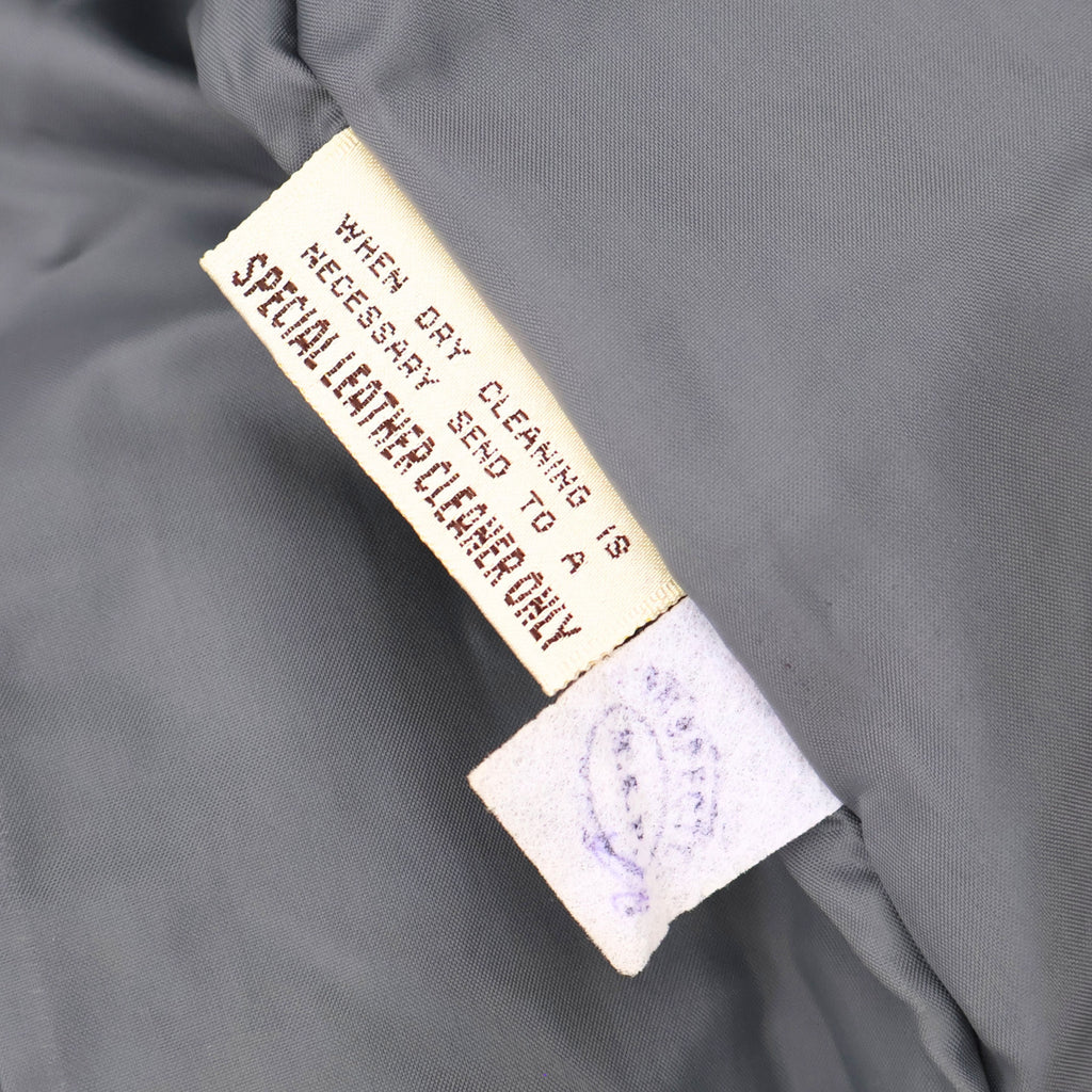Interior care tag of vintage leather blazer indicating leather requires specialized cleaning.