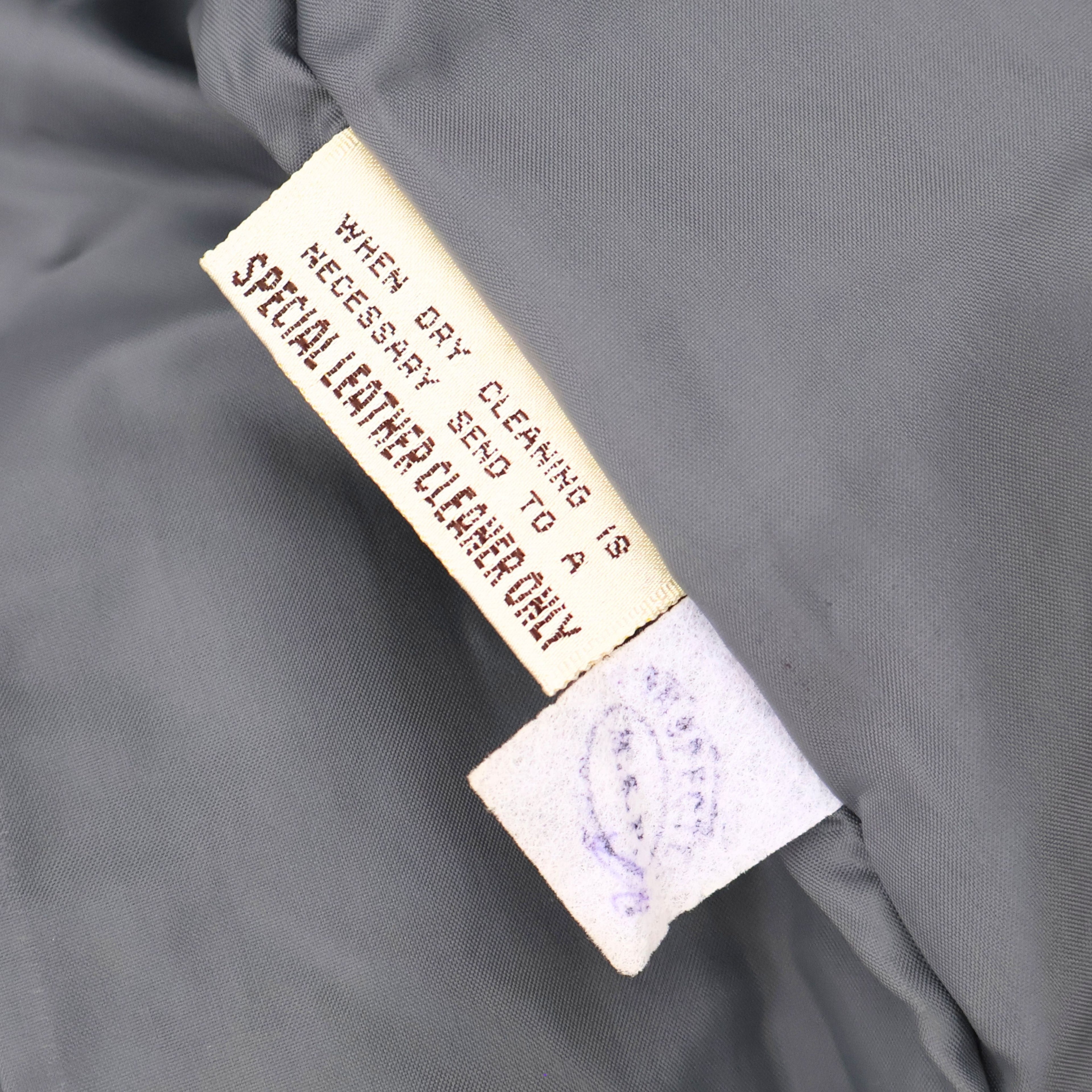 Interior care tag of vintage leather blazer indicating leather requires specialized cleaning.