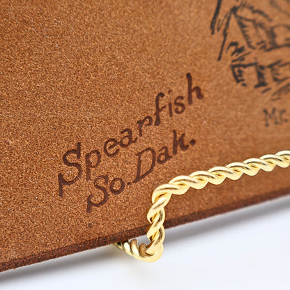 Close up of stamped artwork Spearfish So Dakota on vintage leather photo album