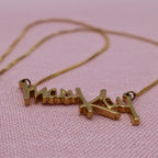 Side angle of vintage Mary Kay distributor necklace showing raised gold script pendant detail and chain.