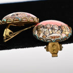 Angled view of vintage Mount Rushmore souvenir clip-on earrings showing the approximately three-quarter inch round size and dimensional domed construction. The raised presidential relief and decorative gold-tone settings illustrate the detailed craftsmanship of this mid-century travel keepsake.