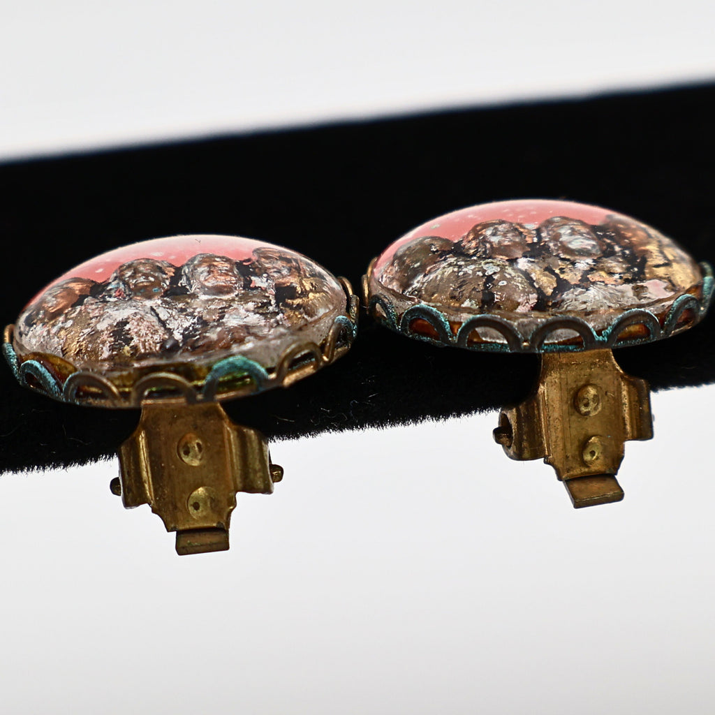 Side profile of vintage Mount Rushmore clip-on earrings displaying the clear domed tops, scalloped gold-tone metal settings, and functioning clip mechanisms. This perspective highlights the dimensional construction and layered scenic design typical of vintage Americana souvenir jewelry.