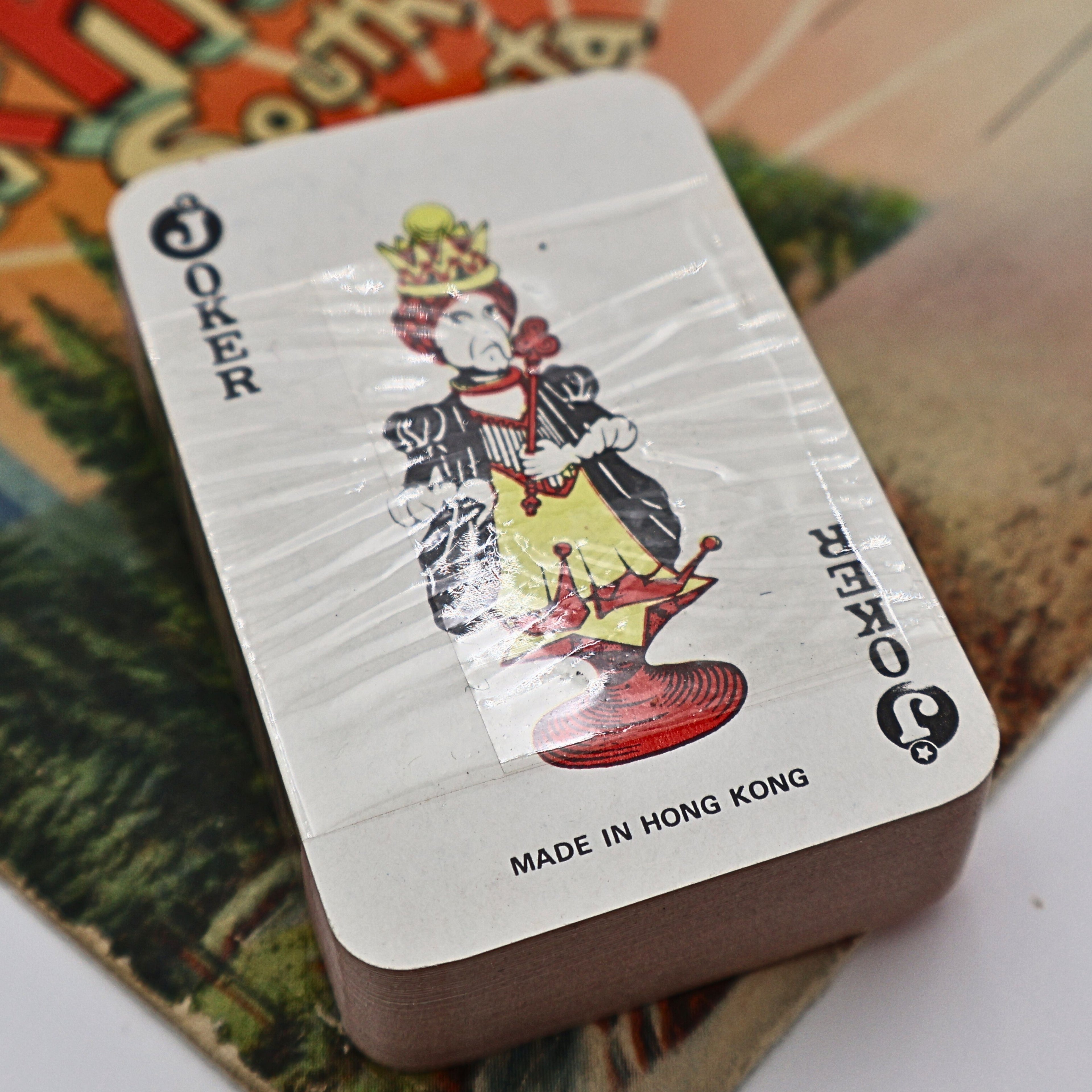 Back of the vintage souvenir playing card deck featuring the Joker card with colorful court illustration and "Made in Hong Kong" printed below. The unopened deck remains wrapped in its original plastic, confirming its vintage travel souvenir origins.