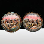 Pair of vintage Mount Rushmore clip-on earrings featuring raised sculpted presidential portraits beneath clear domed covers. The gold-tone scalloped settings frame colorful copper, bronze, green, and rose scenic details, highlighting classic mid-century South Dakota souvenir jewelry displayed from the front.