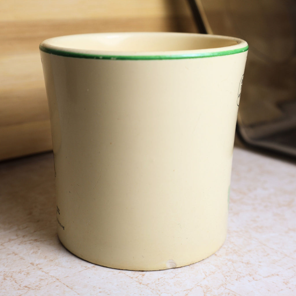 Side profile of vintage cream ceramic Ovaltine mug with classic green rim and smooth cylindrical shape.