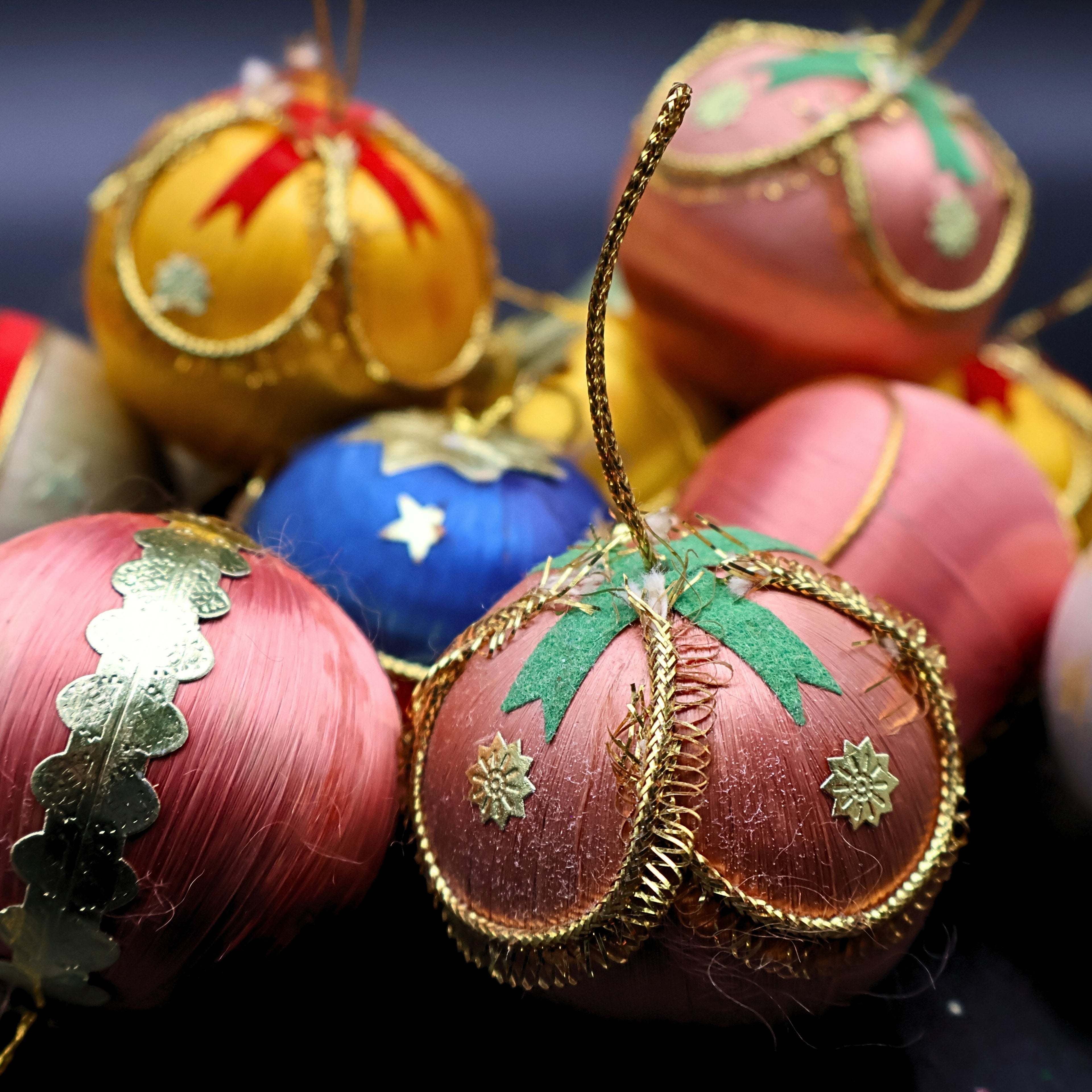 Close up of vintage satin Christmas ornaments featuring detailed gold trim and pastel colors including pink, blue, and gold, showcasing retro holiday decor textures and mid century ornament design