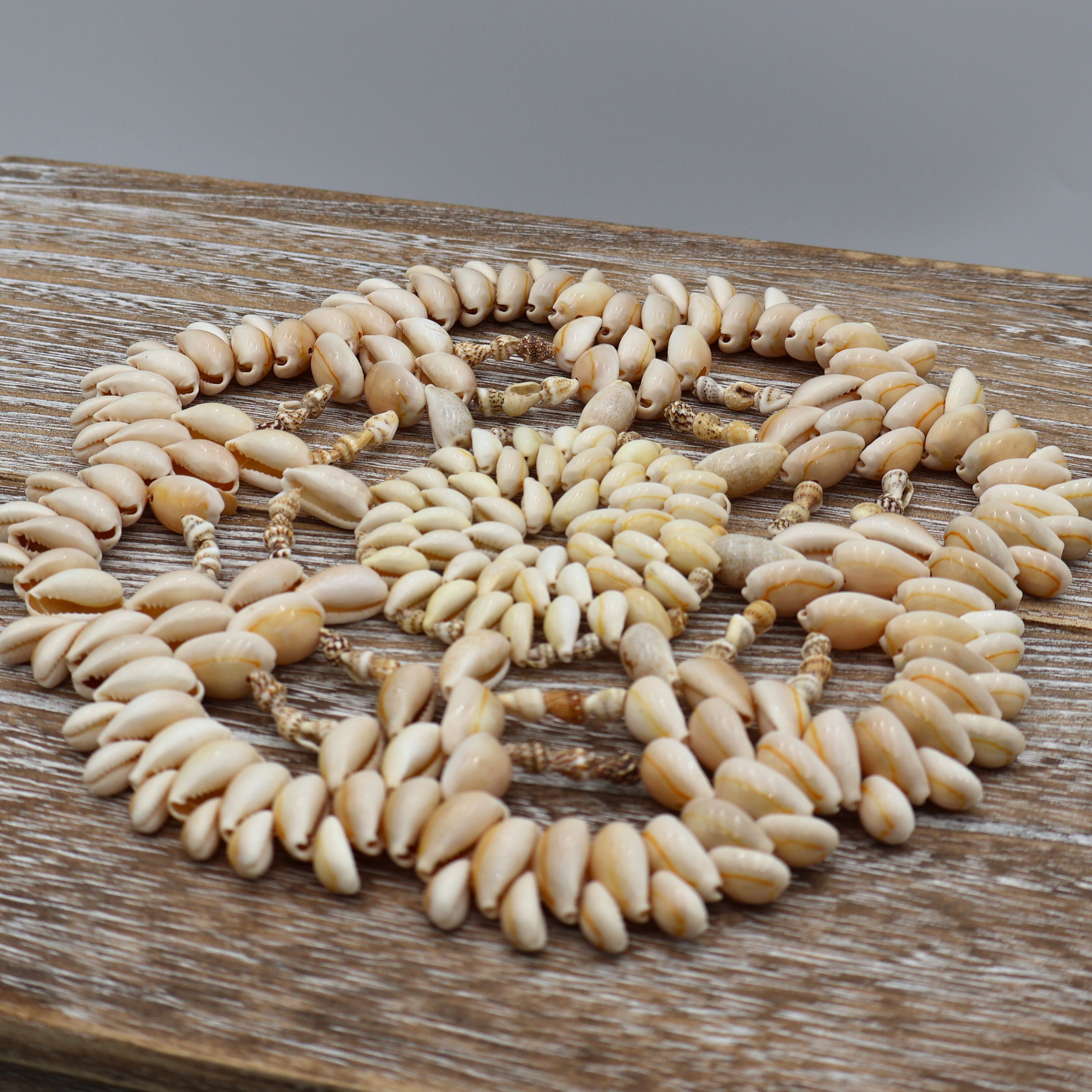 Close-up angled view of the center and outer ring of this handcrafted cowrie shell trivet, highlighting the natural shell textures, subtle ivory tones, and artisan construction that make this vintage coastal decorative hot pad unique.
