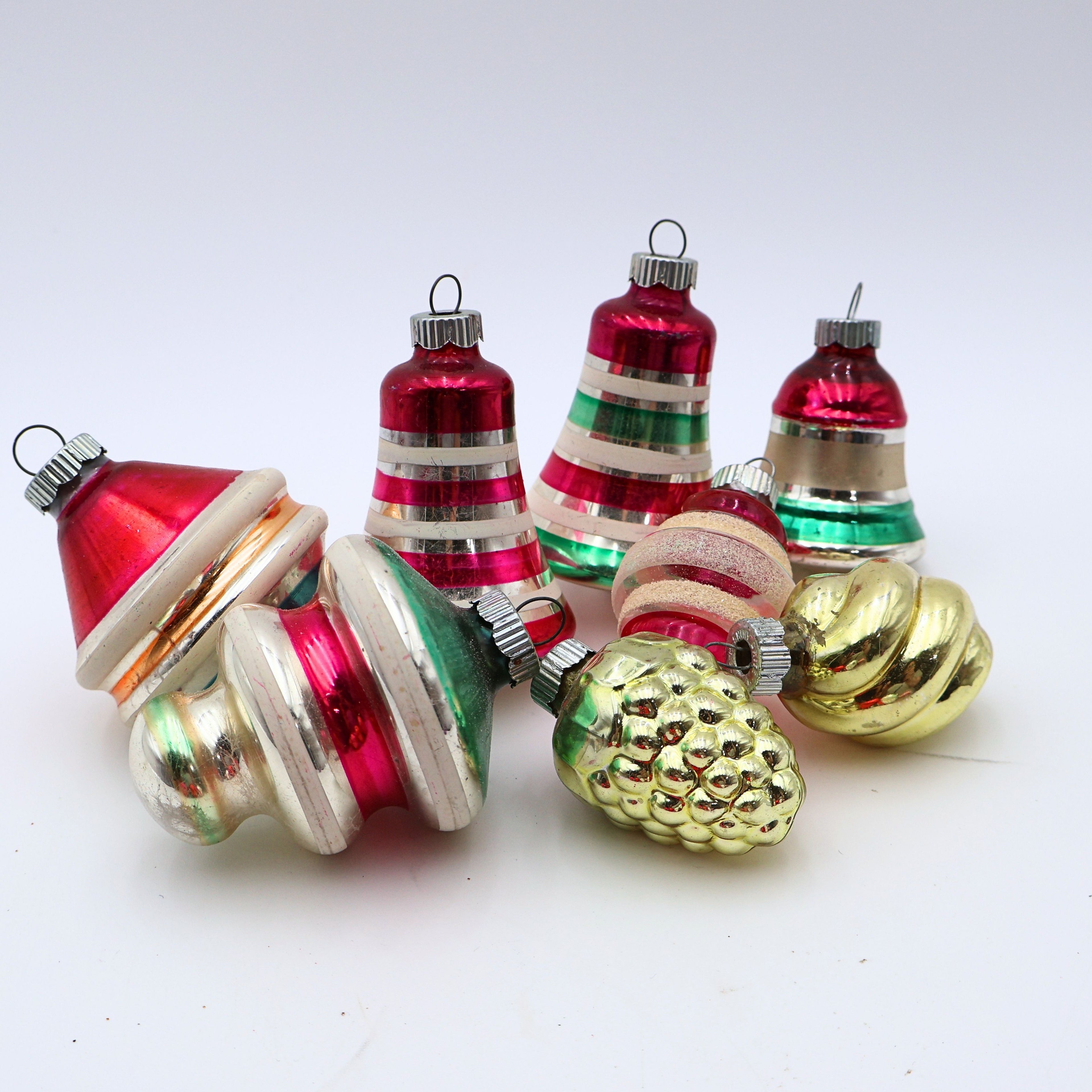 Curated vintage Shiny Brite ornament set featuring striped mercury glass Christmas baubles in pink green gold and silver on white background
